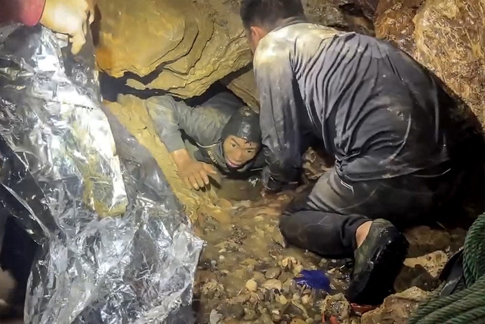 This screengrab made from handout video footage taken on May 29, 2026, and provided by Metta Tham Rescue Kalasin, shows a rescue team freeing one of seven men (L) trapped inside a semi-submerged cave in central Xaysomboun province, northeast of the capital Vientiane. (AFP)