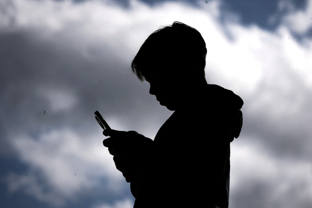 (FILES) This photo taken on October 24, 2025 shows a 14-year-old boy posing at his home near Gosford as he looks at social media on his mobile phone. (AFP)