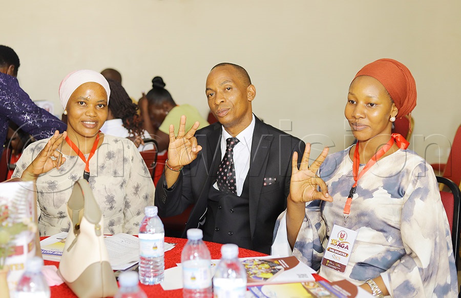 Uganda Woodball Federation General Secretary Adam Kato with two female delegates from the Buganda Region showing the woodball sign at the assembly