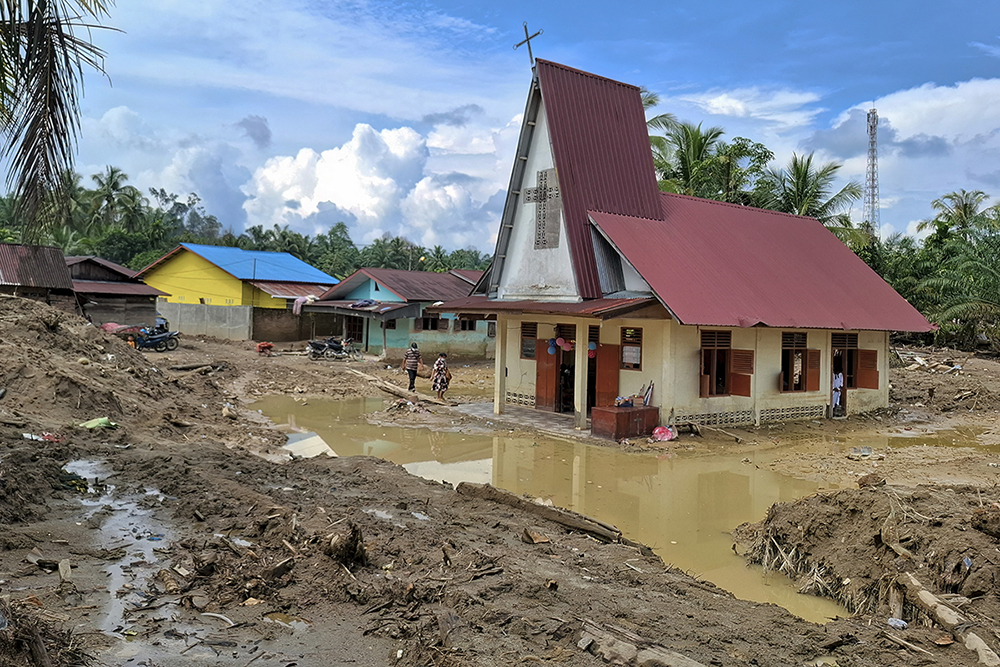 Villagers walk towards the Angkola Protestant Church at Aek Ngadol village, South Tapanuli, North Sumatra province, on Christmas Day December 25, 2025, in the aftermath of massive flooding and landslides in the area. 