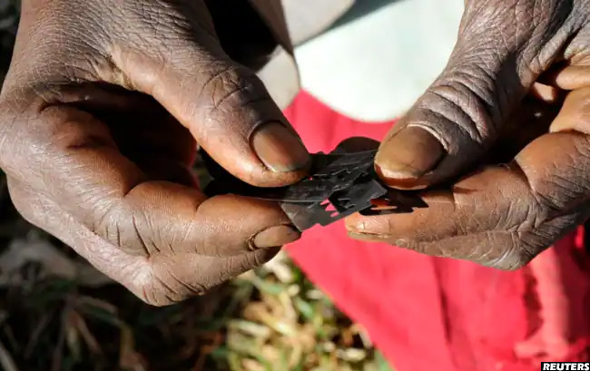 А traditional practitioner holds razor blades used to carry out FGM