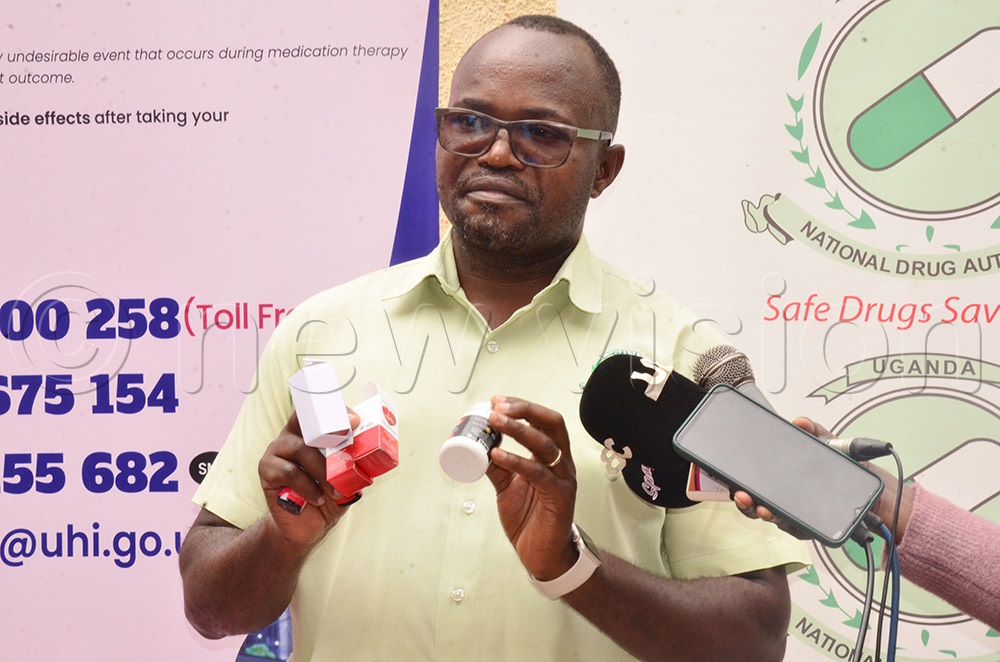 The National Drug Authority (NDA) public relations manager Abbias Rwamwiri displaying the impounded fake drugs at Wandegeya Police station. (Photo by Agnes Kyotalengerire)