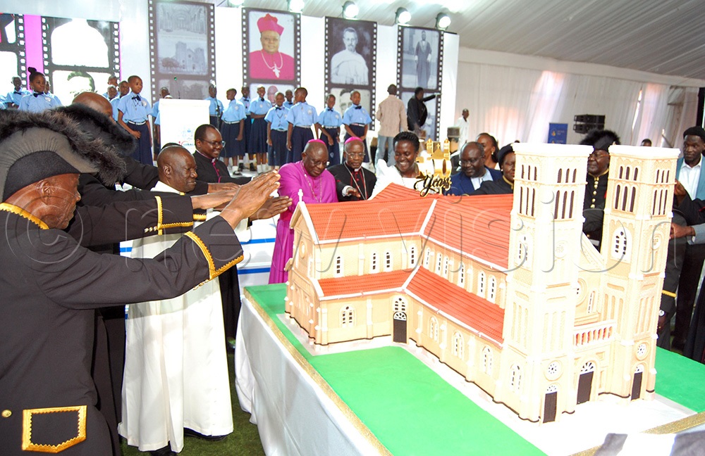 Catholic clearics led by Archbishop Paul Ssemogerere (wearing a purple casSock and a skull cap) and Archbishop Augstine Kasujja (wearing a black cassock) cutting cake with the Papal Knights and leaders of the Catholic laity. (Photo by Mathias Mazinga)