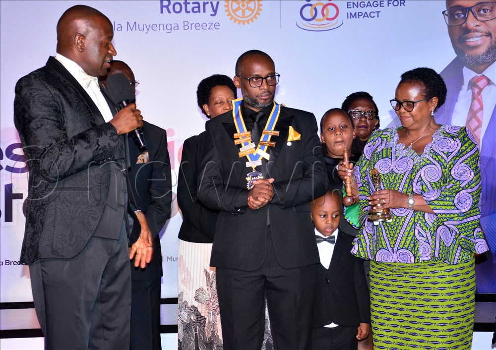 Rukiga District Woman Member of Parliament Sylvia Alinaitwe (R) handing over instruments of Power to Joshua Gavin Wanume as the 14th President of Rotary Club of Kampala Muyenga Breeze at a function held at Nagulu Gardens. On the left is Past Rotary District Governor 9214 Francisco Ssemwanga.