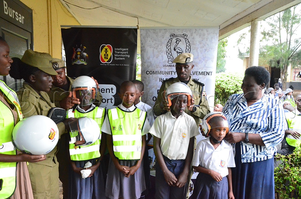 Traffic police spokesperson Michael Kananura and other police officers fitting helmets on some of the pupils heads. (Photo by Jonan Tusingwire)