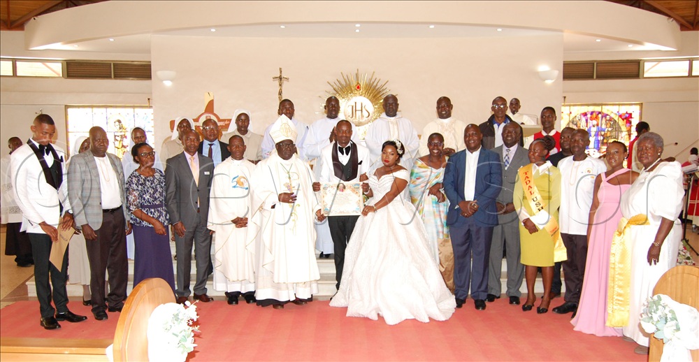 The Archbishop of Tororo Archdiocese, Dr. Emmanuel Obbo (wearing a mitre) shares a photo-moment with the newly wed TADAL couple, Paul Dickson Elibu and Veronica Asekenye, and some of the leaders of TADAL.  This was during the Jubilee Year Pilgrimage organised by the members of Tororo Archdiocese Development Association of the Laity at Uganda Martyrs Catholic Shrine, Munyonyo, in Makindye Division on Saturday, November 8, 2025.