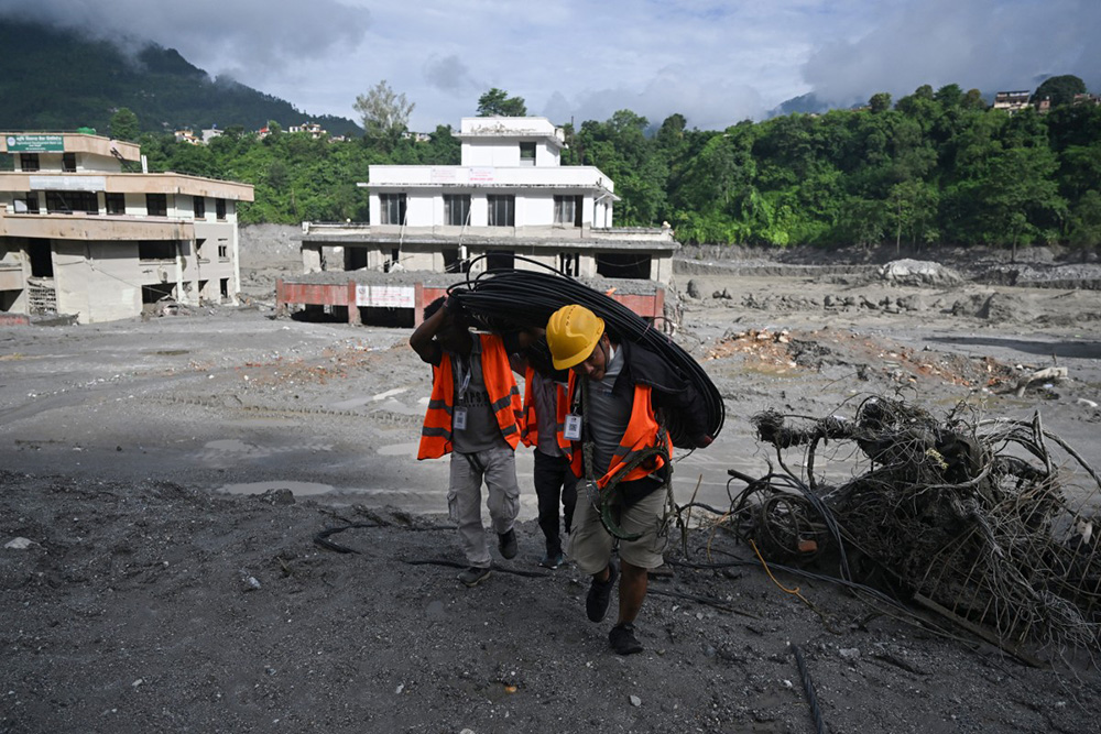  Rescue workers carry cabling at the scene in Trishuli Center in Nepal's Nuwakot district on August 30, 2026, after catastrophic flooding on the Nepal-Tibet border. (Photo by Arun SANKAR / AFP)