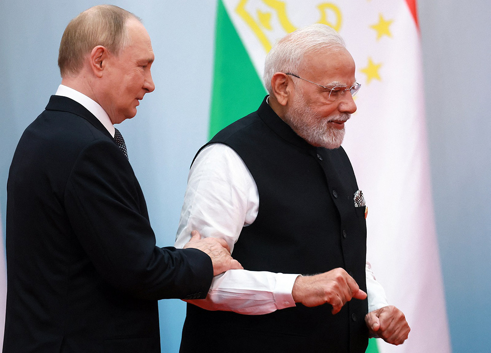 In this pool photograph distributed by the Russian state agency Sputnik, Russia's President Vladimir Putin (L) and  Indian Prime Minister Narendra Modi gather for a group photo during the Shanghai Cooperation Organisation (SCO) Summit in Tianjin on September 1, 2025. (Credit: AFP)
