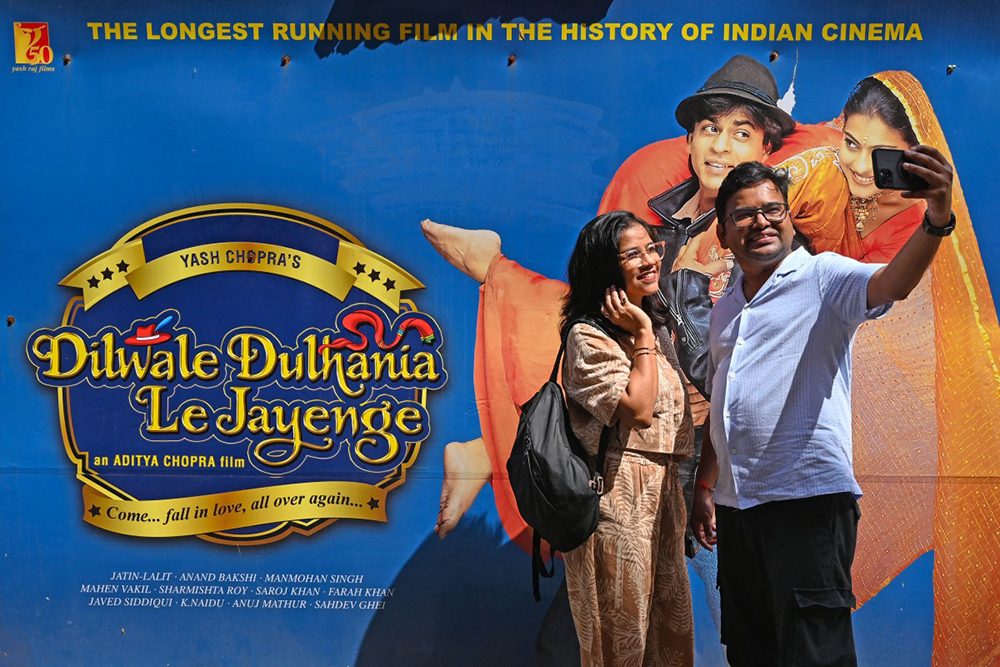 In this picture taken on October 11, 2025, moviegoers take a selfie ahead of the screening of the popular Bollywood Hindi film 'Dilwale Dulhania Le Jayenge' (The brave hearted will take the bride away) at Maratha Mandir theatre in Mumbai. (AFP)