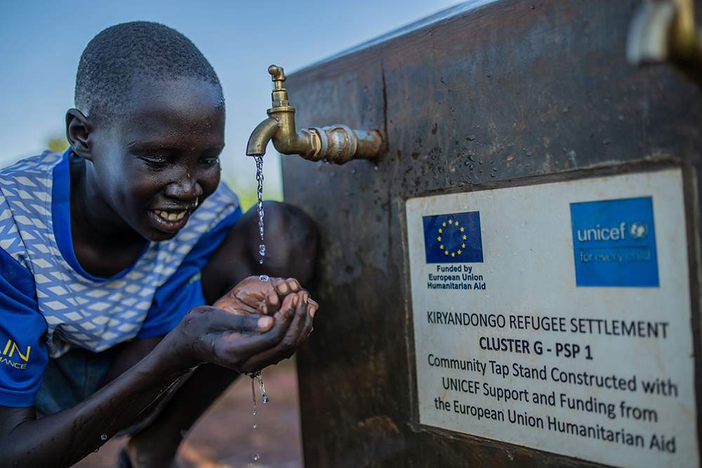 Laul Marol , a 11 year old boy enjoying the water straight from the tap stand constructed by UNICEF with funding from European Union at cluster I in kiryandongo refugee settlement on 14.10.2025 , like Marol children in this community race towards the sound of rushing water, their laughter echoing across the camp as they cup their hands to drink, splash their faces, and wash the dust from their legs, a simple joy made possible by clean, running water.
