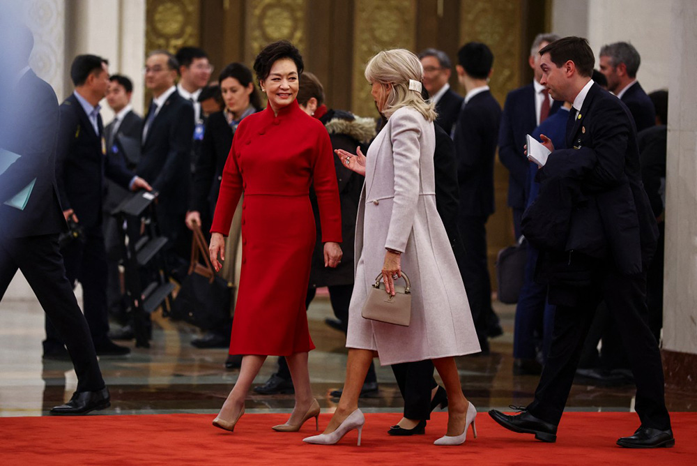 Peng Liyuan (L), wife of China's President Xi Jinping, and Brigitte Macron (R), wife of France's President Emmanuel Macron, attend a welcome ceremony at the Great Hall of the People in Beijing on December 4, 2025. (Photo by Sarah Meyssonnier / AFP)