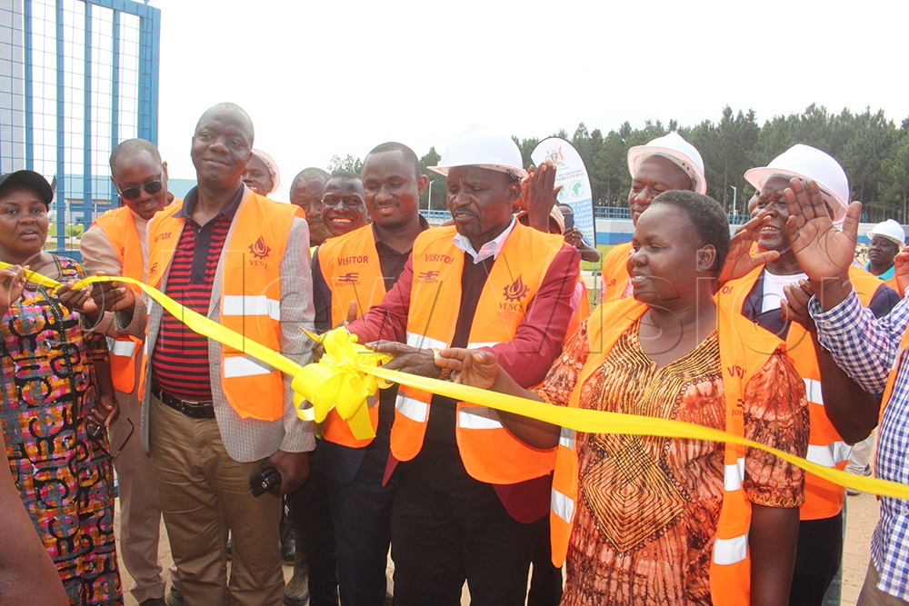 The Chair of the Parliamentary Committee on National Economy, John Bosco Ikoju (centre), cuts the tape at the launch of the water system at Bugondha. (PHOTOS BY TOM GWEBAYANGA)