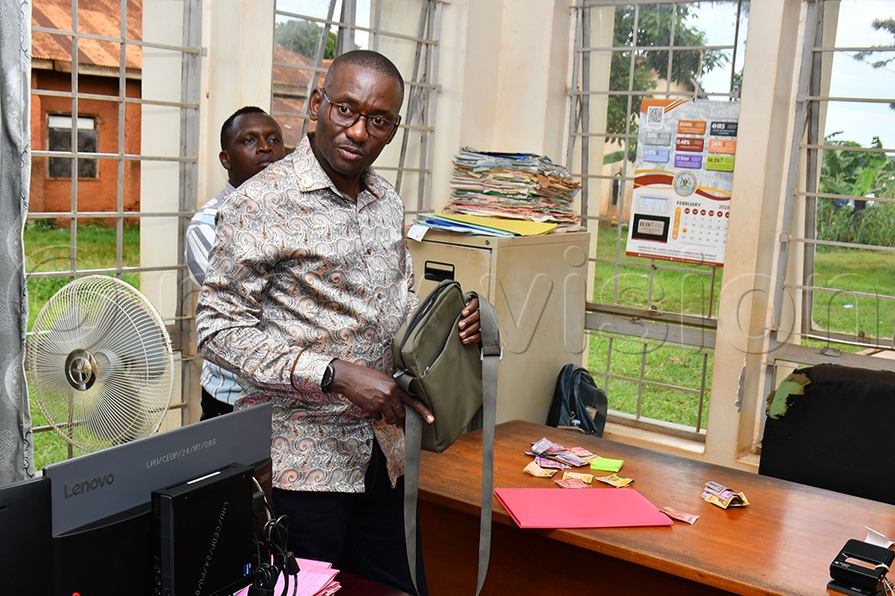 The Director of Ombudsman Affairs, Kakooza Savior Ntensibe showing Wangoli's small green bag that contained money extorted from people to fast-track land services at the Ministry Zonal Office in Jinja City. (Photo by Donald Kiirya)