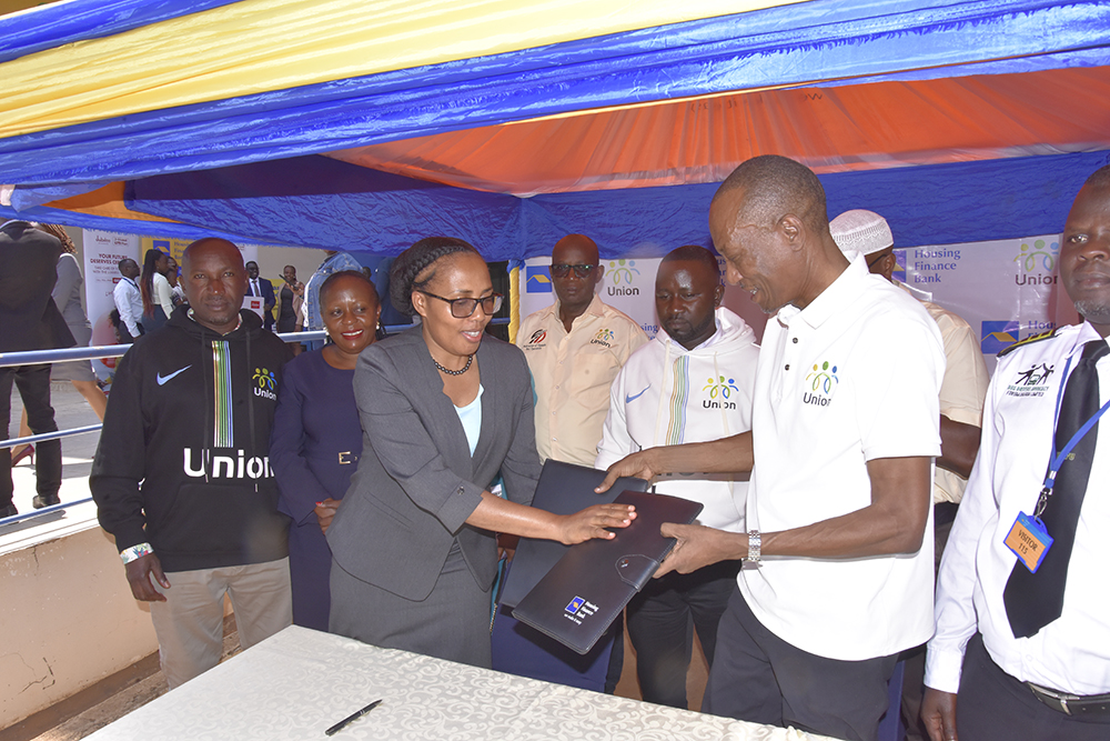 Ayebazibwe (left) exchanging documents with Ssenoga after signing the MOU at HFB head offices in Kololo. (Courtesy)