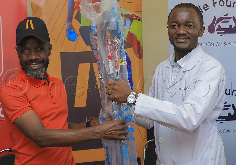 Beyanga hands over some of the clutches donated to road crash victims at Mulago National Referral Hospital to Dr Mubiru. (Credit: Douglas Mubiru)