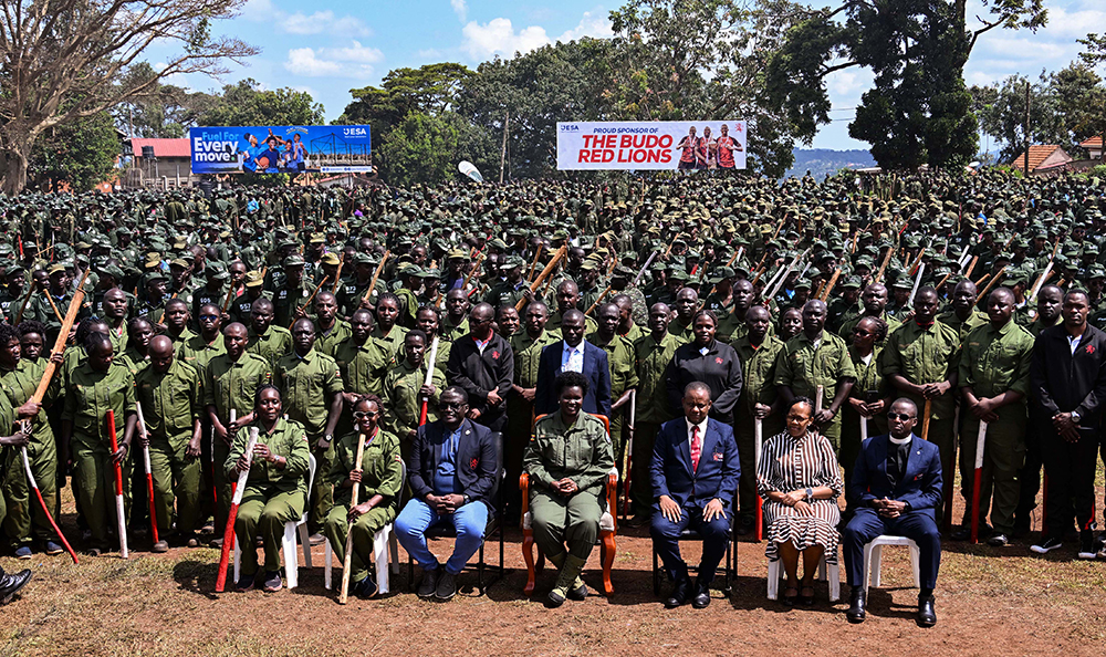 Commissioner Patriotism Helen Seku (C), the Headteacher and staff of Kings College Buddo pose for a photo with over 2500 patriotism students during their passout at Buddo on Saturday. (PPU Photo)