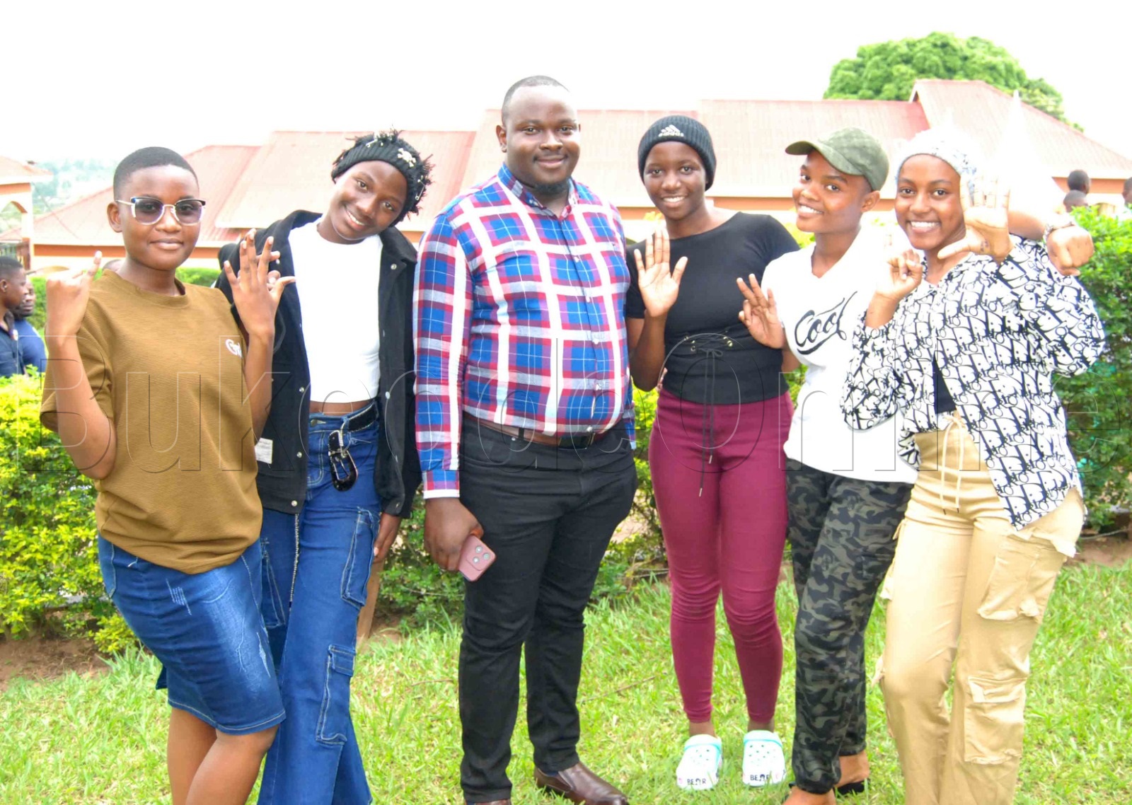 Abayizi b'essomero lya Rines Secondary School nga bali wamu n'omu ku badayirekita Robert Byamukama (wakati). Ku kkono ye Angella Ndagire eyafunye 6As 4Bs, owokubiri ku kkono ye Desire Nabukeera yafunye 8As 1B, owokusatu ku ddyo ye Maria Namanda yafunye 8As 1B, owokubiri ku ddyo ye Stecia Zalwango yafunye 5As 4Bs ate ku ddyo ye Gloria Mutesi yafunye 6A 4B