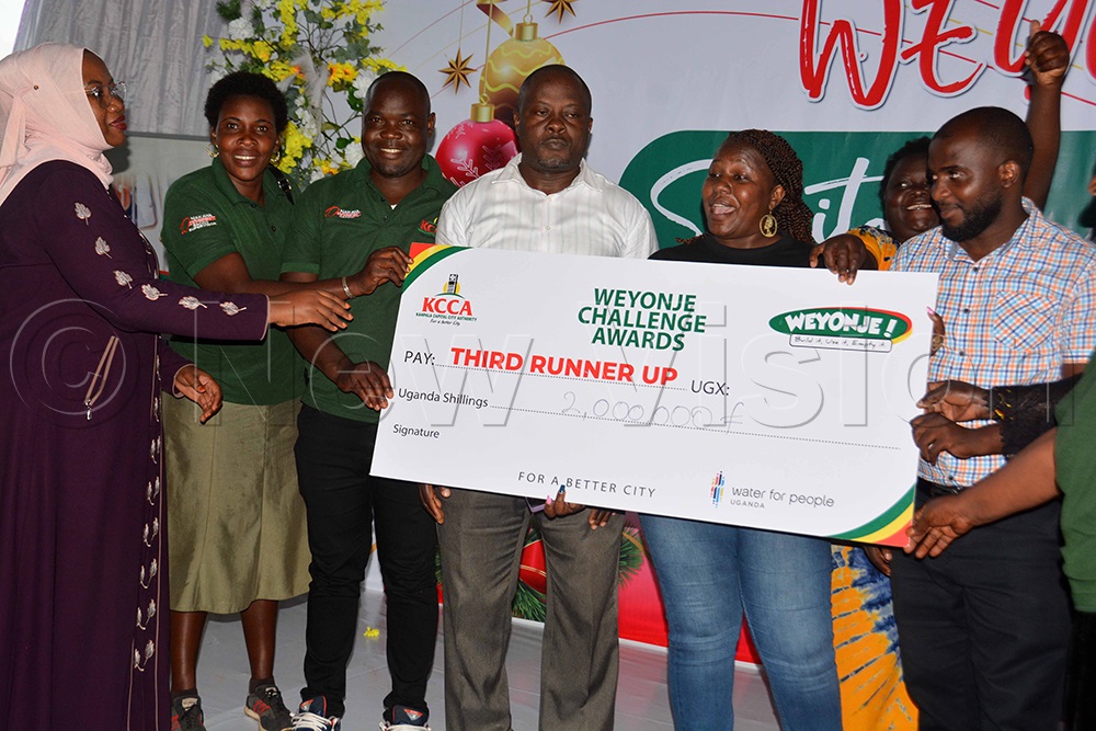 The KCCA executive director, Sharifah Buzeki (left), hands over a dummy cheque of sh2m to Nakawa Division officials for being the third runners up of the sanitation challenge 2025 awards during the awards handover ceremony at Kitante Primary school on December 22, 2025. (Photo by Francis Emorut)