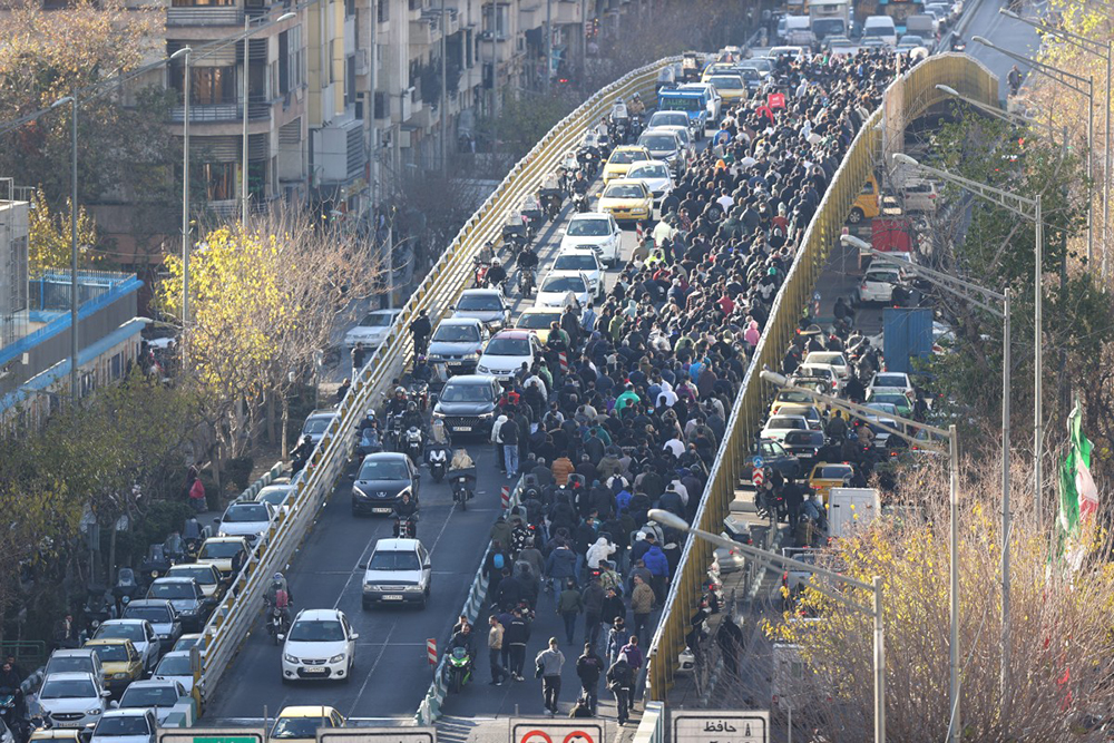 Shopkeepers and traders walk over a bridge during a protest against the economic conditions and Iran's embattled currency in Tehran on December 29, 2025. (AFP)
