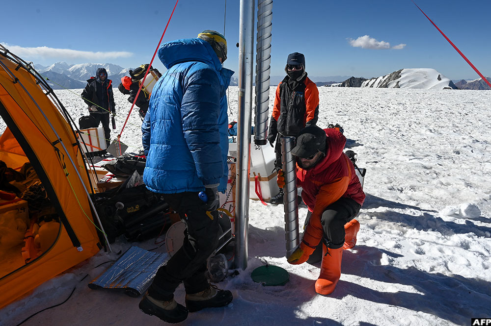 Expedition chief Evan Miles (R) and Russia's paleoclimatologist and glaciologist Stanislav Kutuzov, (L) taking a "carrot" of ice out of the Pamir glacier as part of the expedition "Pamir-Ice-Memory" in Kon Chukurbashi, Eastern Tadjikistan, on September 24, 2025