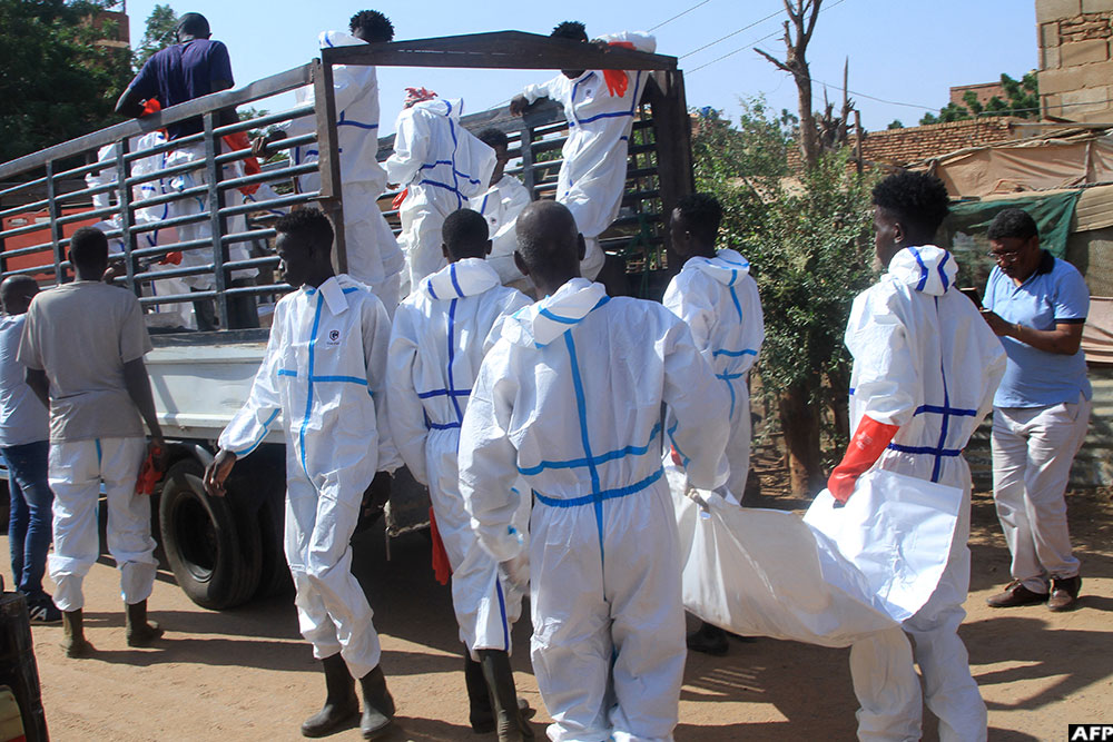 Employees working for the authorities load a body bag into the back of a lorry as bodies are dug up from an emergency burial site inside a school, to be buried in public cemeteries, in Sudan's capital Khartoum on December 8, 2025. (AFP)