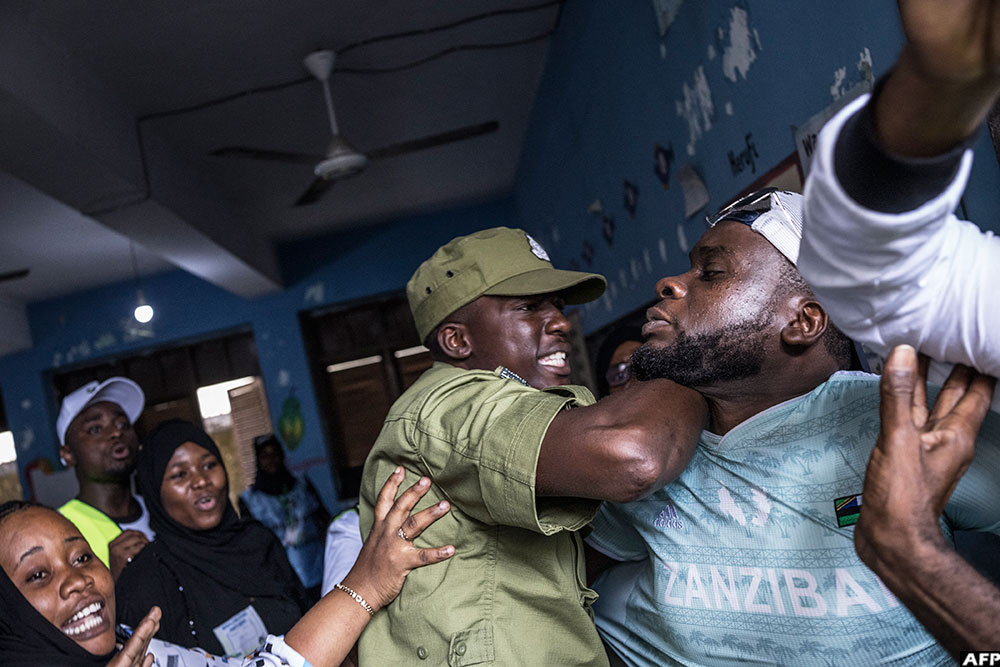 A Tanzanian police officer stops a man accused by electoral officials of attempting to taint the voting process at a polling station in Stone Town on October 29, 2025