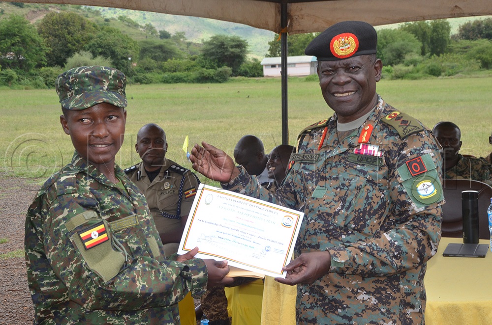 Maj. Gen. Wilberforce Sserukuma hands over a certificate to the best female officer, Precious Birungi, during the pass-out of nine commissioned officers at Moroto barracks, April 6, 2026. (Photo by Olandason Wanyama)