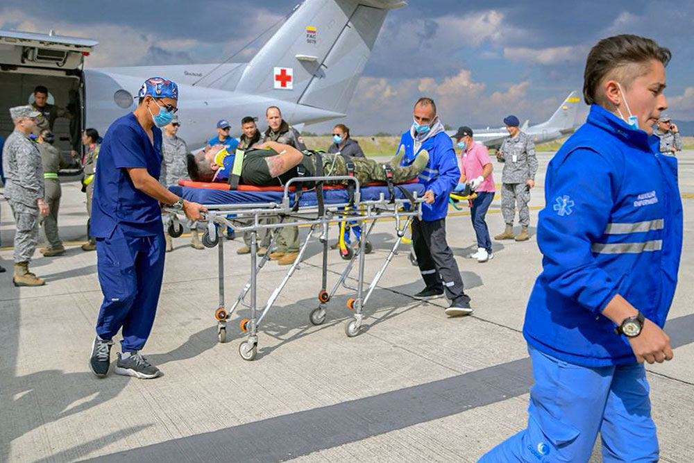 Members of the Colombian Aerospace Force and paramedics carrying an injured person at CATAM air base in Bogota, Colombia, on March 23, 2026, following the plane crash. (AFP/Colombian Armed Forces)