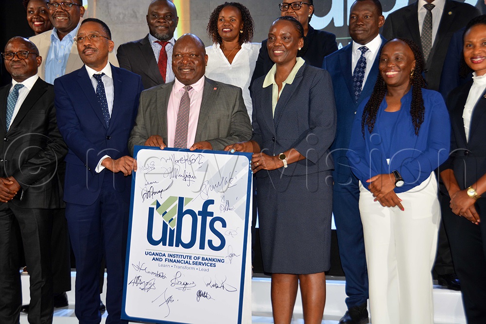 (L-R): The chairman board of directors UIBFS and chief executive officer Housing Finance Bank Michael Mugabi, the director of Finance Bank of Uganda Richard Byarugaba and the chief executive officer of Uganda Institute of Banking and Financial Services (UIBFS) Goretti Masadde holding a portrait of new company's logo during its unveiling in Kampala. (Photo by Francis Emorut)