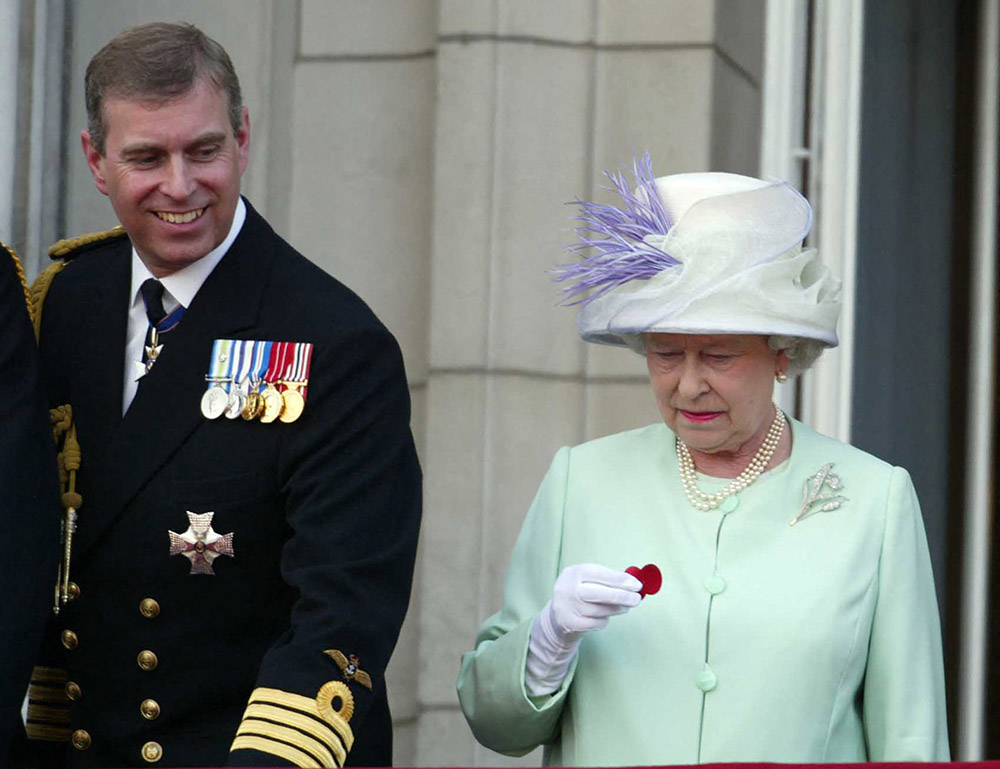 Queen Elizath II hold a poppy dropped from a Lancaster bombe as she stands next to Prince Andrew on the balcony of Buckingham Palace during the celebrations marking the end of World War II in London on July 10, 2005. (AFP/Files)
