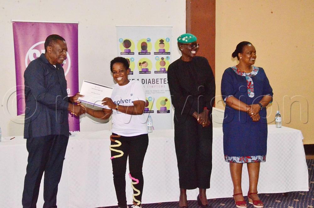  The Director General of health services at the Ministry of Heath Dr Charles Olaro handing over a certificate to a participant after training. (Photo by Agnes Kyotalengerire)