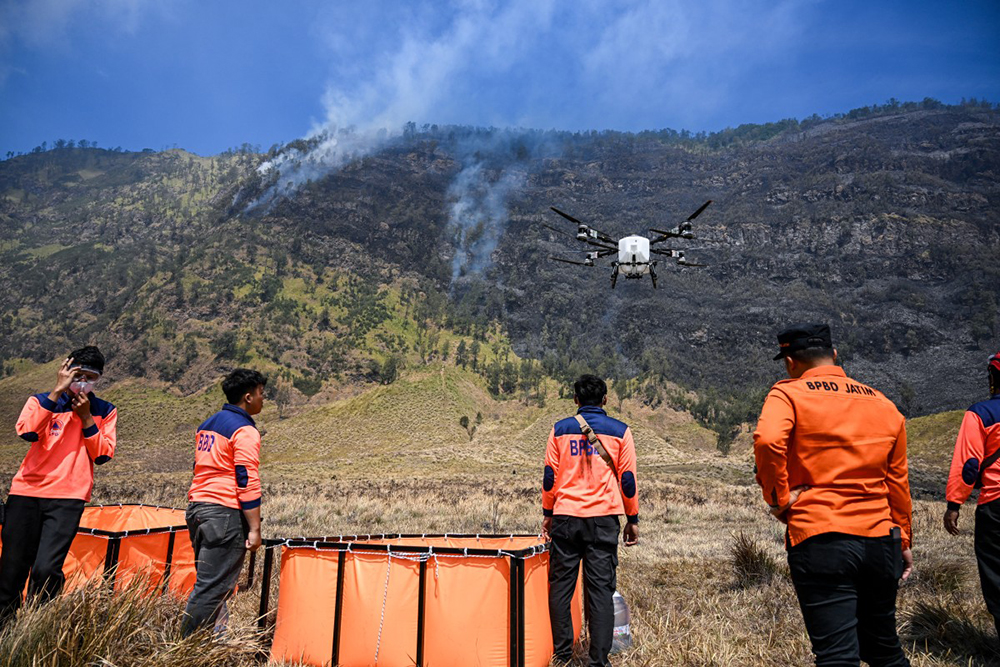 Officials from the East Java Provincial Disaster Management Agency fly a drone carrying water to battle a wildfire in the Bromo Tengger Semeru National Park near Mount Bromo in Probolinggo, East Java province on August 6, 2026.
