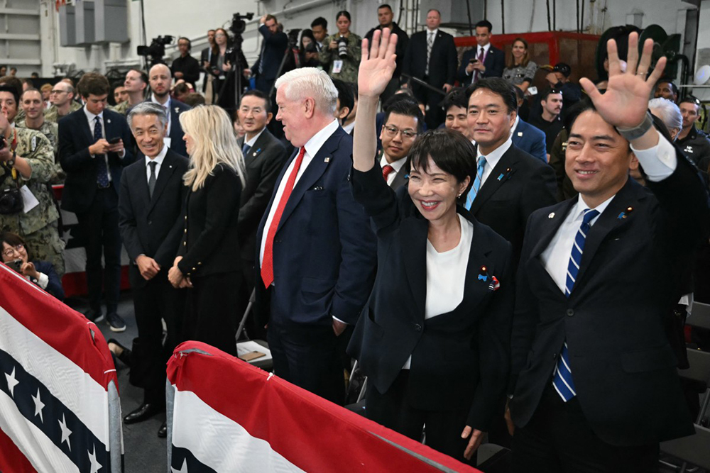 (R-L) Japan's Defense Minister Shinjiro Koizumi, Japan's Prime Minister Sanae Takaichi, and US Ambassador to Japan George Glass react to US President Donald Trump's speech in front of US Navy personnel on board the US Navy's USS George Washington aircraft carrier at the US naval base in Yokosuka on October 28, 2025.