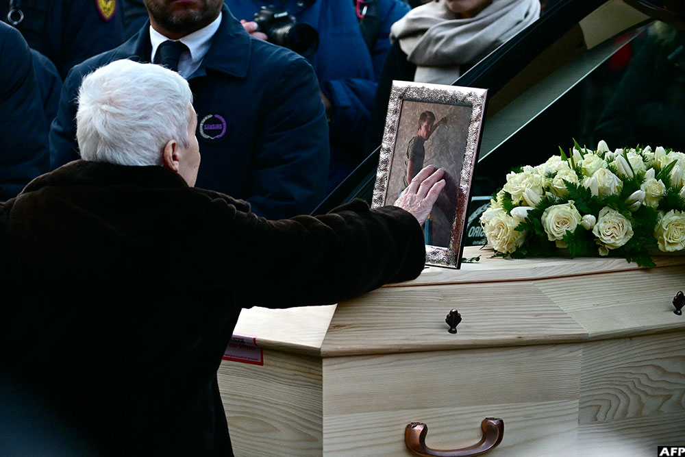 A woman touches the coffin of 16-year-old Achille Barosi, one of the Italian victims of the Crans-Montana New Year fire, at the end of the funeral outside the Basilica of Sant'Ambrogio, in Milan on January 7, 2026