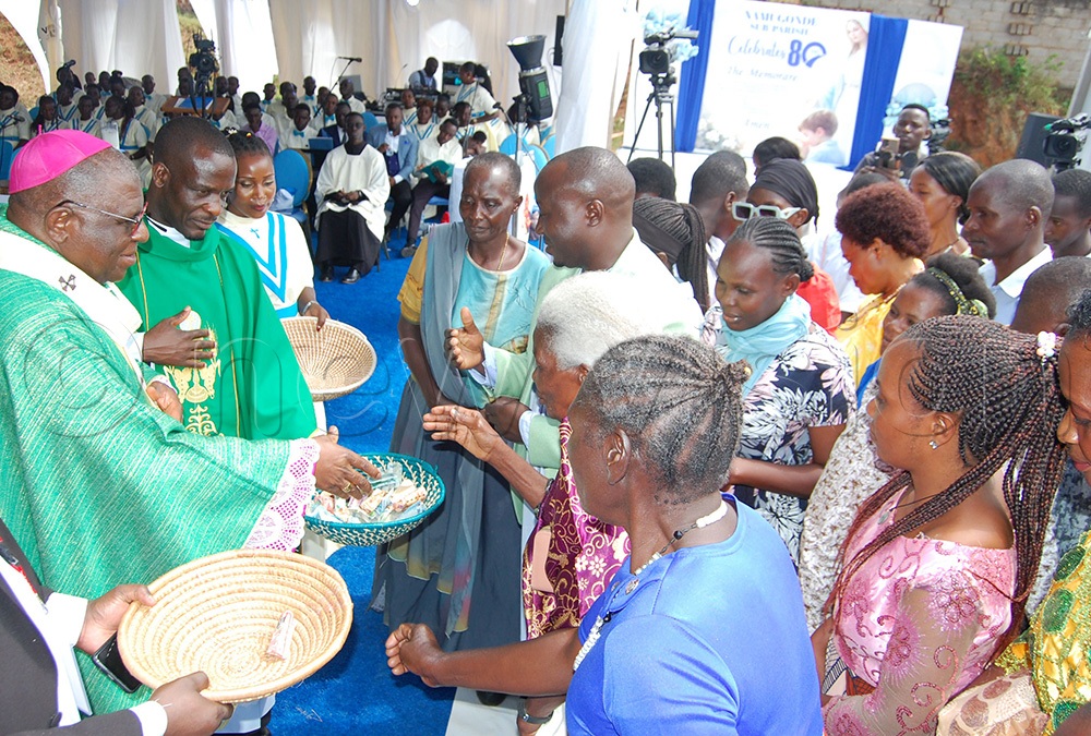 Archbishop Paul Ssemogerere (wearing a skull-cap) receiving cash for the construction of the proposed perimeter wall of Namugonde sub-parish during the church's 80th anniversary celebration on Sunday, June 28, 2026. (Photo by Mathias Mazinga)
