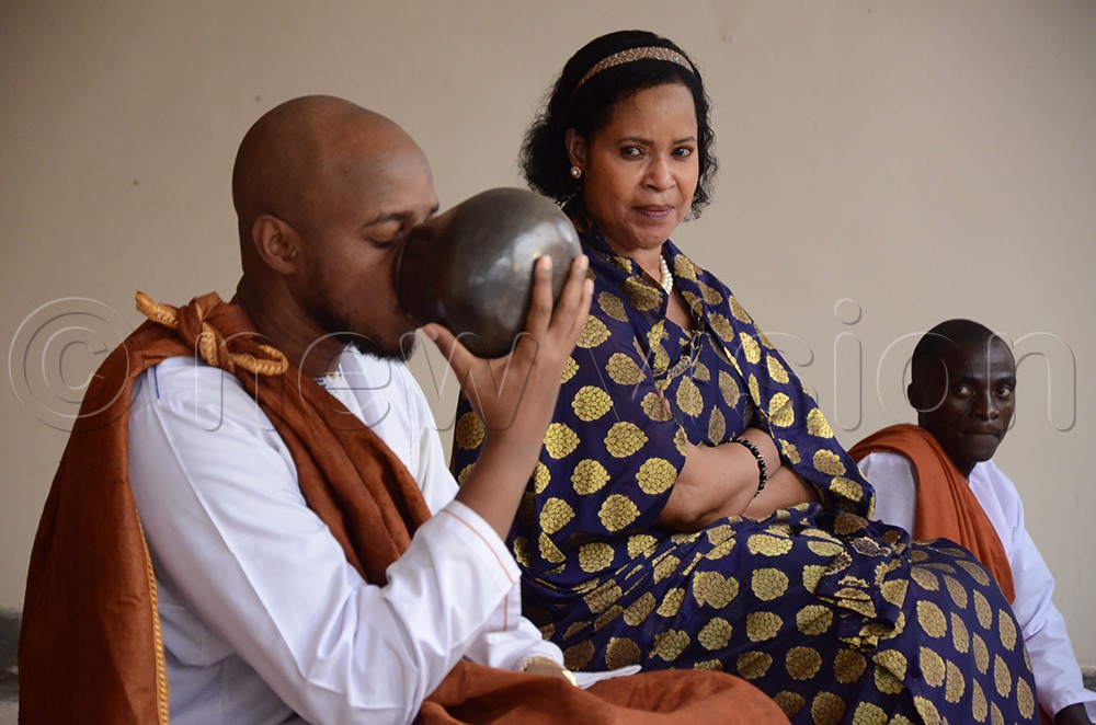 King Oyo drinking milk from a calabash as part of the rituals as Queen mother Best kemigisa looks on. (New Vision Archives)