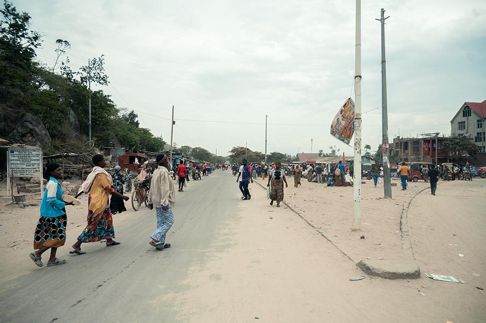 Commuters walk along a road in Uvira on December 9, 2025. Intense fighting is taking place on Tuesday in the eastern Democratic Republic of Congo (DRC), with the M23 group, supported by the Rwandan army, continuing its rapid advance towards Uvira, a strategic Congolese city located near the border with neighboring Burundi and now under threat. (Credit: AFP)