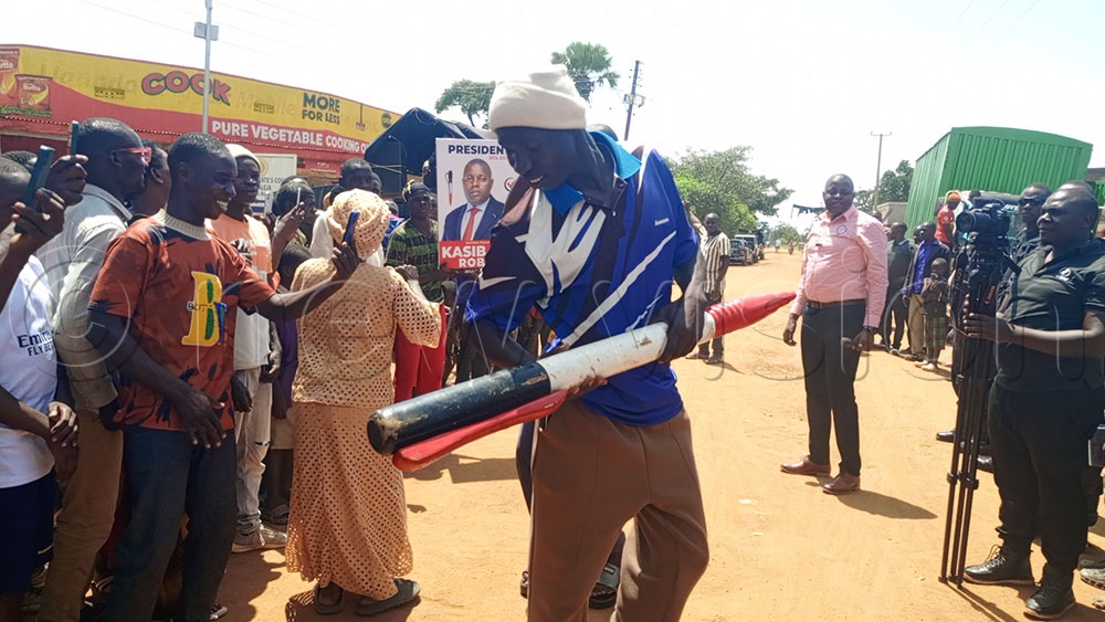 A supporter of NPP's Robert Kasibante holds a giant dummy pen, the party's symbol, in Butaleja district on November 7, 2025. (Credit: George Ofwono)