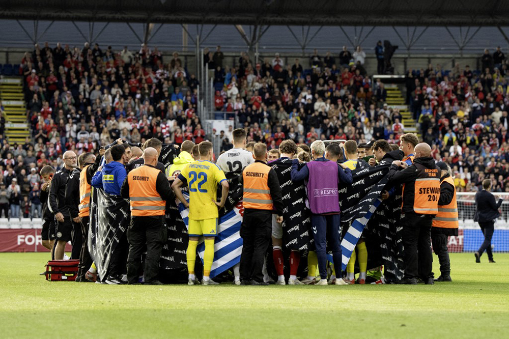 Players from Denmark and Ukraine form a circle around Christian Eriksen after he collapsed during the football international match between Denmark and Ukraine at Odense Stadium on Sunday, June 7, 2026. (AFP)