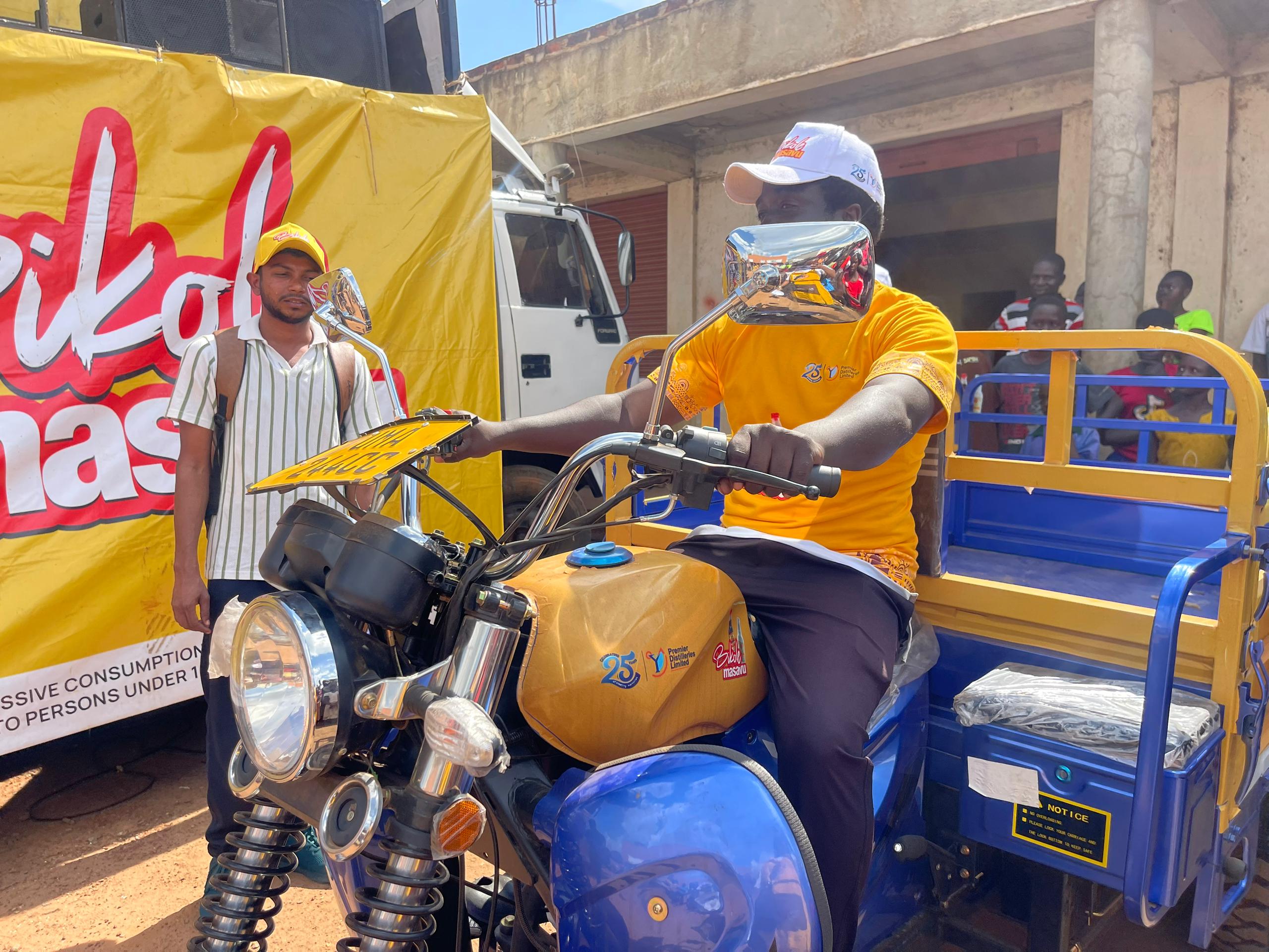 Emmanuel Ogwal (R) receives a brand new Tuk Tuk after winning from the Bikole Masavu Promotion by Premier Distilleries Limited