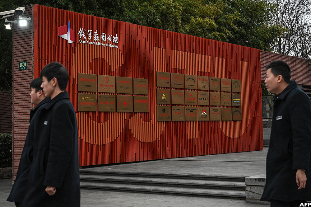 Security guards walk past signage for the Qian Xuesen Library at Shanghai Jiao Tong University in Shanghai