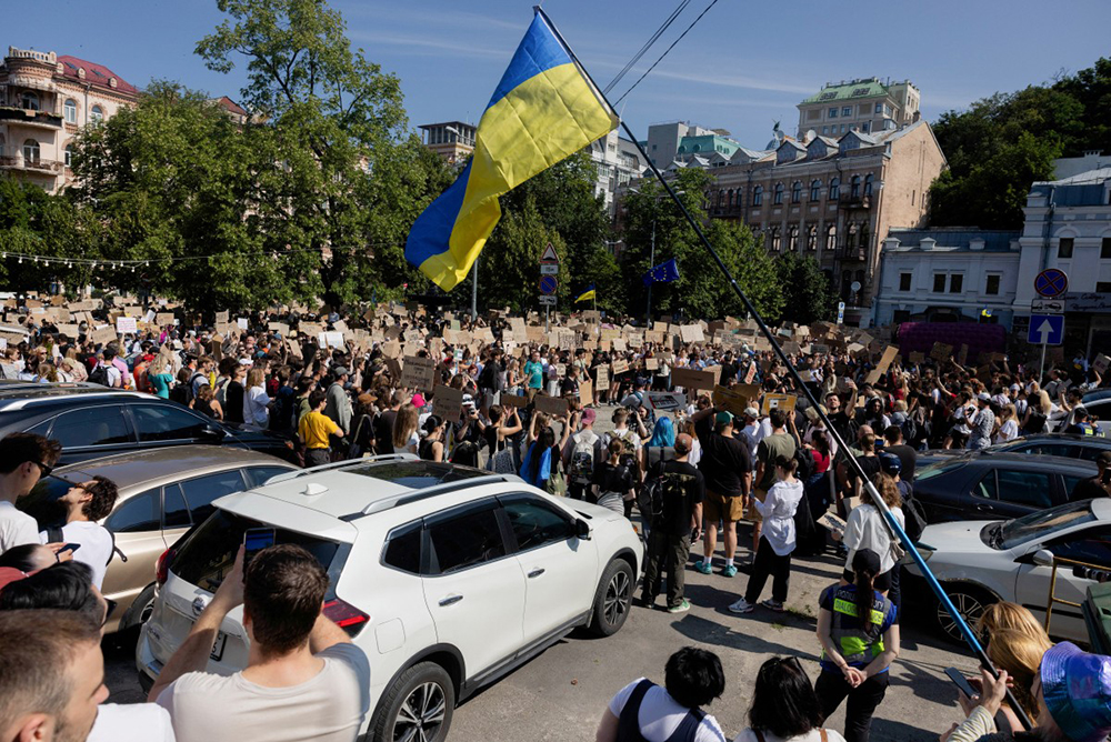 Protesters chant slogans and wave a Ukranian national flag as they take part in a demonstration against Ukraine's President Volodymyr Zelensky's decision to dismiss Ukraine's Defence Minister Mykhailo Fedorov, in Kyiv on July 16, 2026, amid the Russian invasion of Ukraine. 