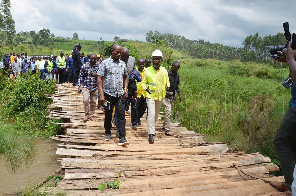 Deputy speaker Thomas Tayebwa walking through Ncwera, a temporary bridge made of wood which residents constructed after their concrete bridge was destroyed by floods in 2021. (Photo by Abdulkarim Ssengendo)