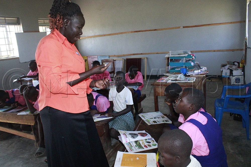 A special needs teacher uses sign language to support learners with hearing impairments during a lesson. (Photo by Ritah Mukasa)