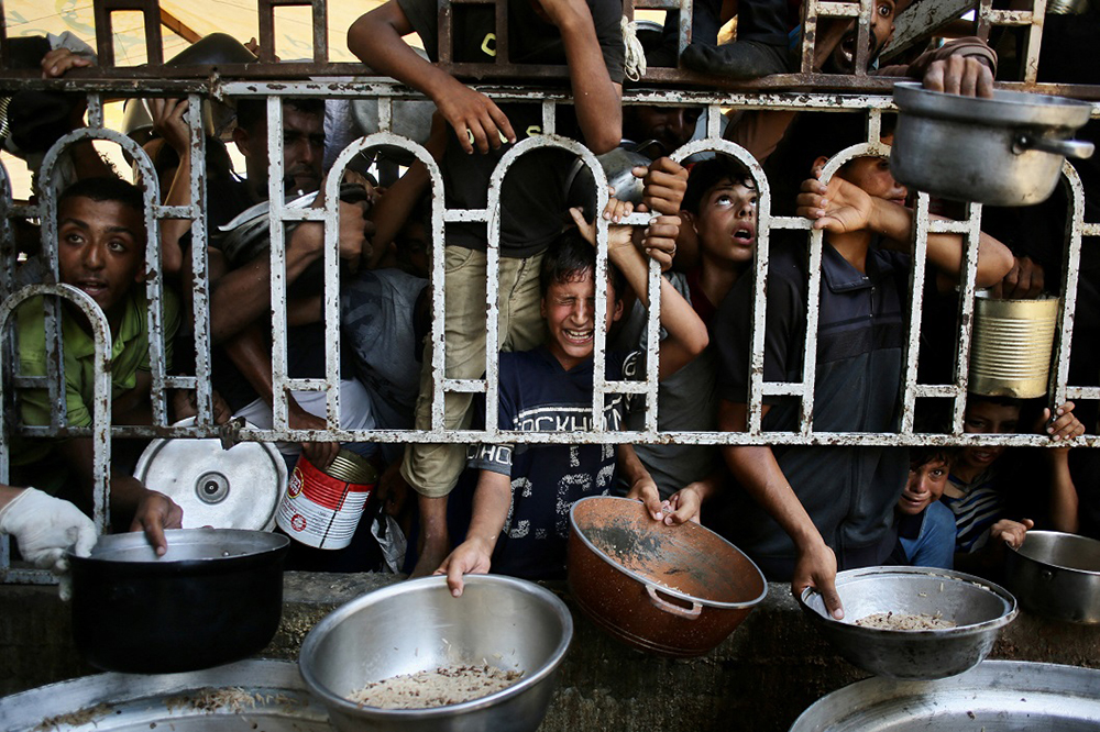 Palestinian children wait for a meal at a charity kitchen in the Mawasi area of Khan Yunis in the southern Gaza Strip on July 22, 2025.
