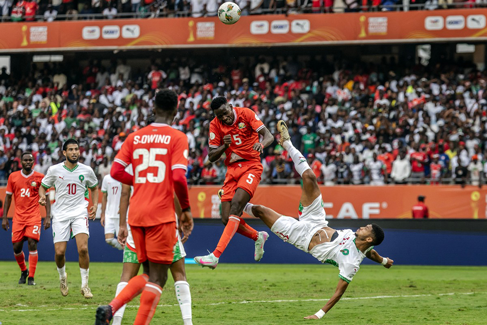Kenya's defender #5 Alphonse Otieno Omija (C) clears the ball as Morocco's forward #11 El Kaabi Youness (R) attempts an overhead kick during the African Nations Championship (CHAN) group stage football match between Kenya and Morocco at Kasarani Stadium in Nairobi, on August 10, 2025. (Photo by AFP)
