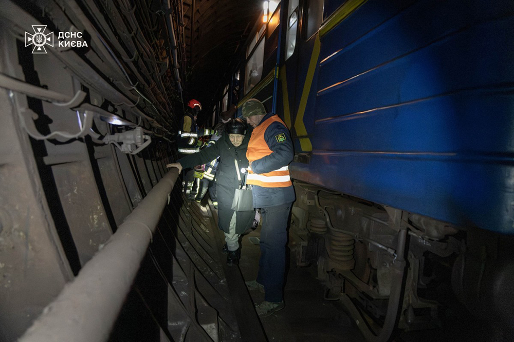 Rescuers anad subway workers helping people to leave subway through tunnels during mass power outages in Kyiv, amid the Russian invasion of Ukraine.