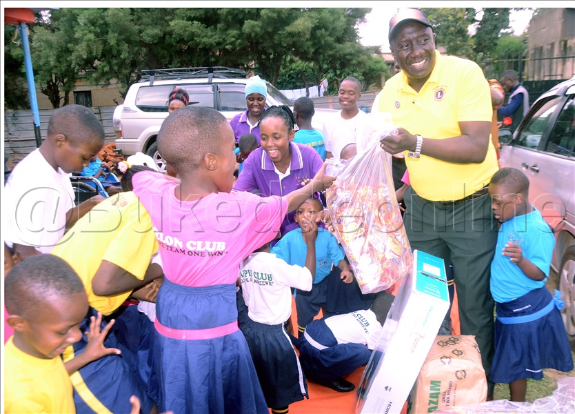 Dr. Emmanuel Kisaame (wakati) Pulezidenti Wa Lions Club Of Kampala Victoria Luzira Ng&rsquo; Agabira Ebyokulya Eri Abaana Bano.