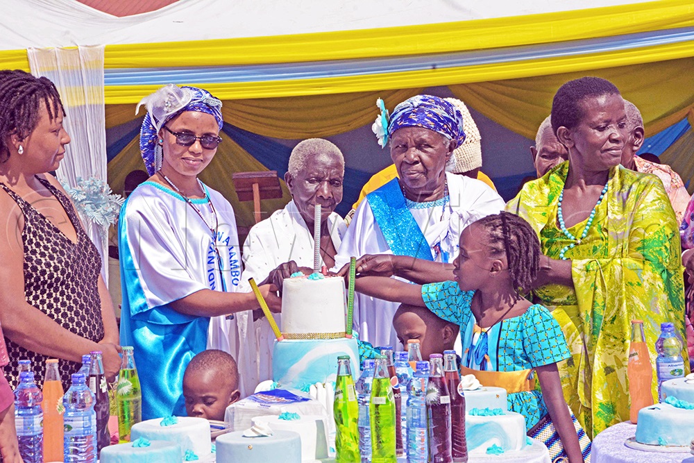 Beatrice Kiiza Amooti (Third right) with sisters, children and grandchildren cutting a cake. (Photo by Peter Abaanabasazi)