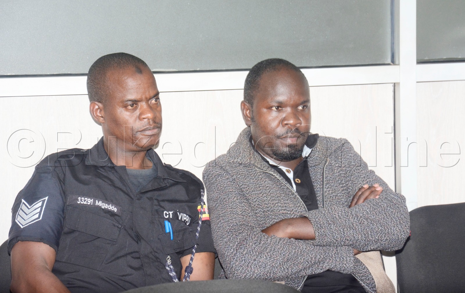 Ssekikubo (ku ddyo) ng'atudde n'omuserikale amukuuma mu kkooti.
